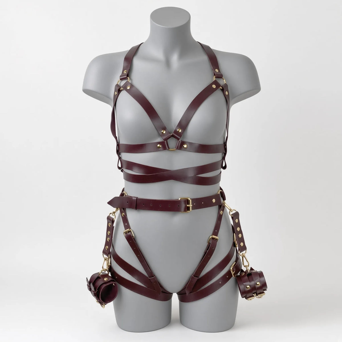 Ensemble de soumission fétiche pour chiot Alpha Restraint composé d'un baudrier cage de poitrine croisé, d'une large ceinture abdominale avec sangles de cuisses et d'entraves poignets en simili cuir bordeaux de face sur mannequin.