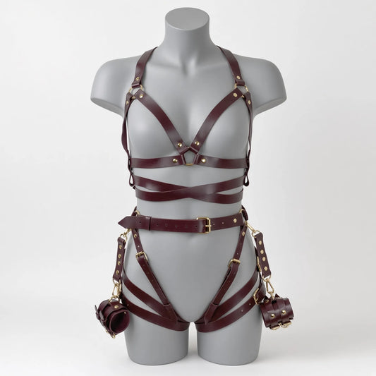 Ensemble de soumission fétiche pour chiot Alpha Restraint composé d'un baudrier cage de poitrine croisé, d'une large ceinture abdominale avec sangles de cuisses et d'entraves poignets en simili cuir bordeaux de face sur mannequin.