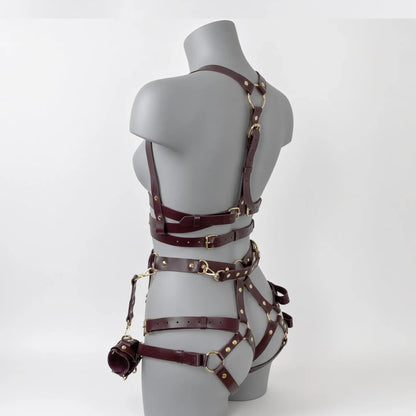 Vue trois-quarts du harnais cage complet de dressage petplay Alpha Restraint en cuir PU bordeaux avec sangles de maintien cuisses, baudrier de torse et menottes de poignets pour pup soumise sur buste de mannequin blanc.