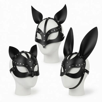 Trois masques de petplay en cuir noir avec rivets sur mannequins blancs représentant les variantes de la meute : oreilles de chat (kitten play), oreilles de chien (puppy play) et oreilles de lapin (bunny play).