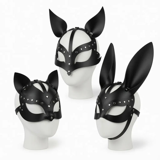 Trois masques de petplay en cuir noir avec rivets sur mannequins blancs représentant les variantes de la meute : oreilles de chat (kitten play), oreilles de chien (puppy play) et oreilles de lapin (bunny play).